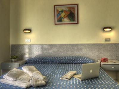 Camera d'albergo con letto, laptop e asciugamani piegati.