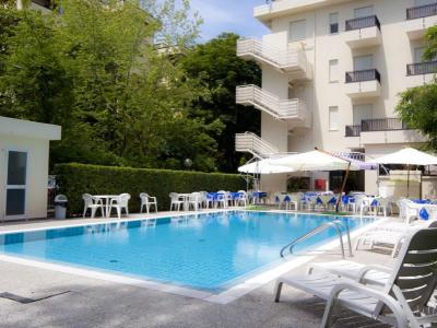 Piscina all'aperto con sedie e ombrelloni vicino a un edificio.