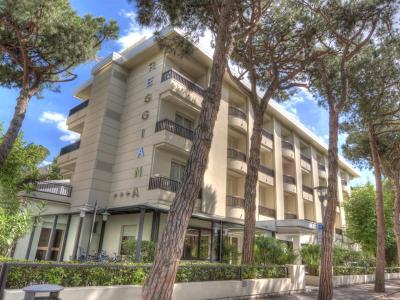 Edificio moderno circondato da alberi alti e cielo sereno.