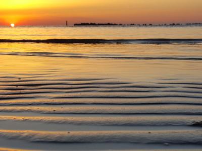 Tramonto sul mare con riflessi dorati e onde leggere.