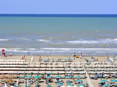 Spiaggia affollata con ombrelloni e mare calmo.