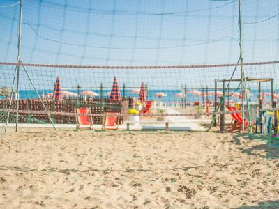 Campo da beach volley sulla spiaggia con ombrelloni colorati.