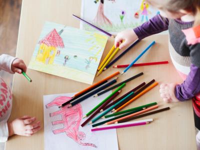 Bambini colorano disegni con matite colorate su un tavolo.