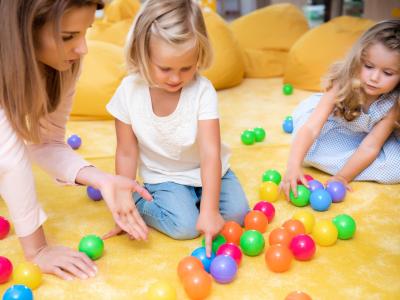 Bambini giocano con palline colorate su un tappeto giallo.