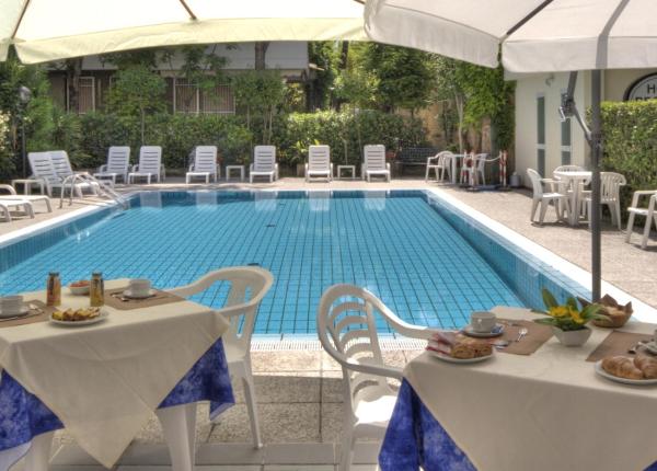 Piscina all'aperto con tavoli apparecchiati per colazione.