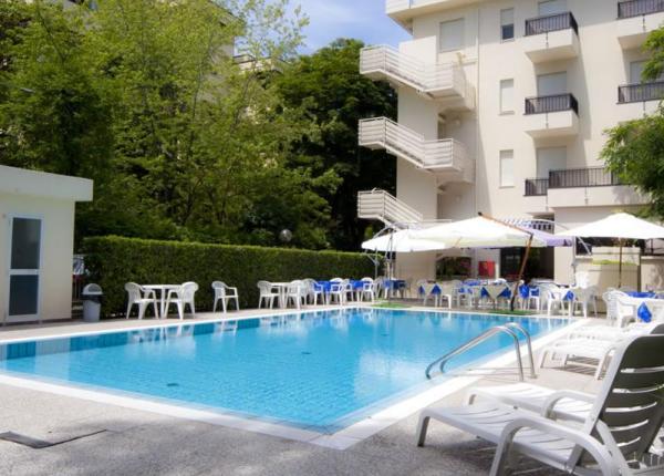 Piscina all'aperto con sedie e ombrelloni vicino a un edificio.