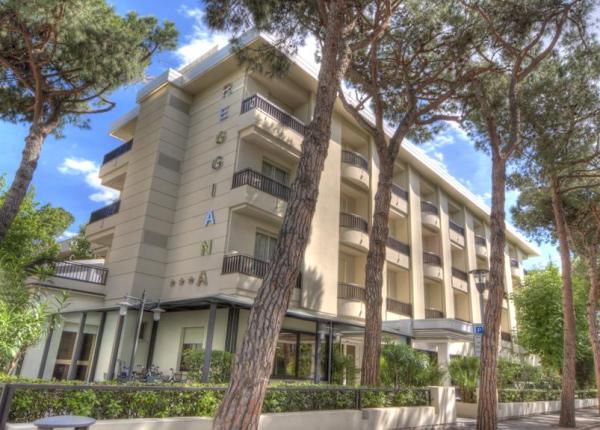 Edificio moderno circondato da alberi alti e cielo sereno.