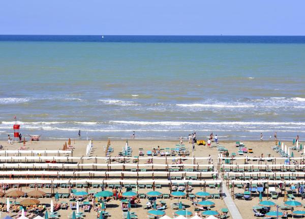 Spiaggia affollata con ombrelloni e mare calmo.