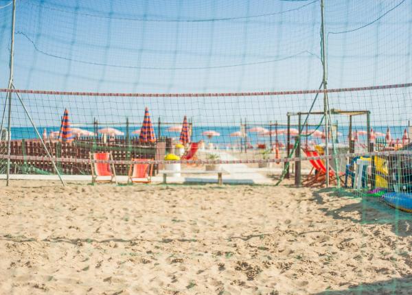 Campo da beach volley sulla spiaggia con ombrelloni colorati.